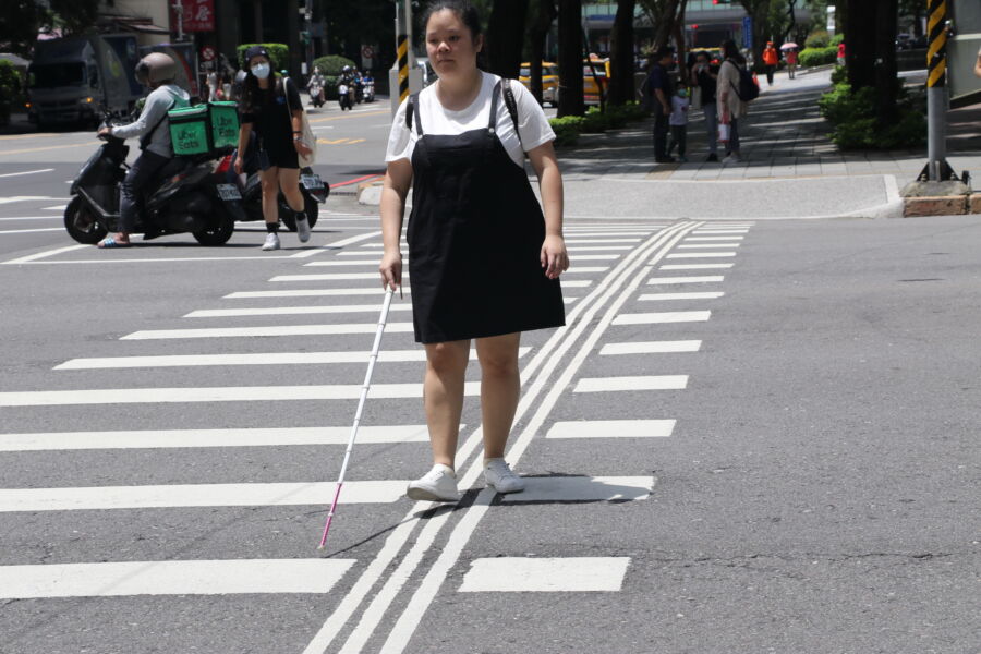 圖／視障者施芸婷在通過十字路口時走「導盲行穿線」，認為更有所依循、也更安全。（新北市政府社會局提供）