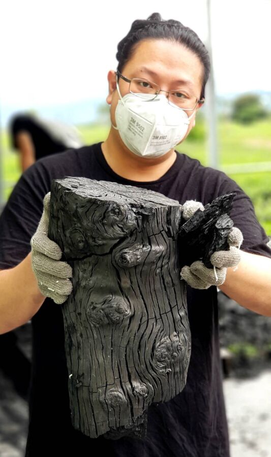 圖／手工龍眼木炭與阿賢。（呂明賢提供）
