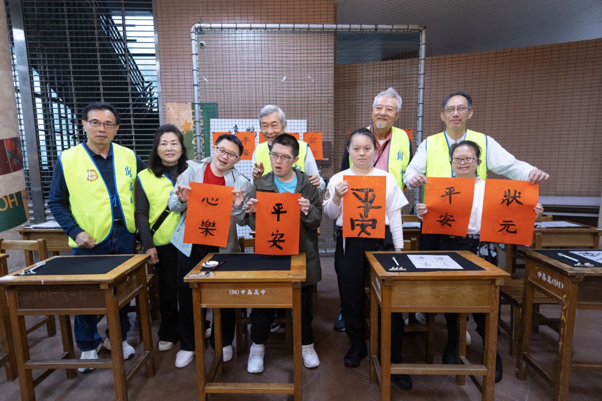 圖/副市長林奕華逛園遊會,於總監林振邦、活動主委金文徵及華朋扶輪社吉祥物「朋鵬」陪同下,在「逸鵝書屋」書法攤揮毫。(松山社區大學提供)