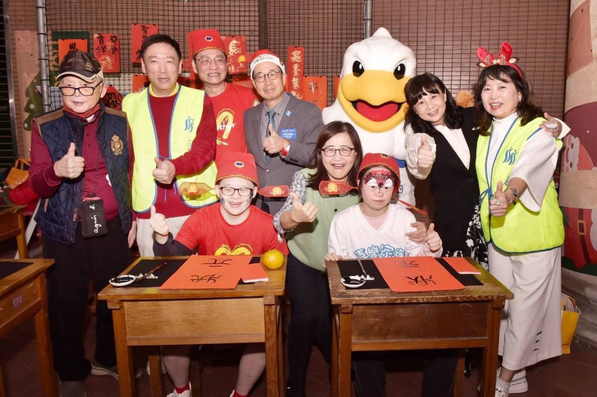 圖/副市長林奕華逛園遊會,於總監林振邦、活動主委金文徵及華朋扶輪社吉祥物「朋鵬」陪同下,在「逸鵝書屋」書法攤揮毫。(松山社區大學 提供)