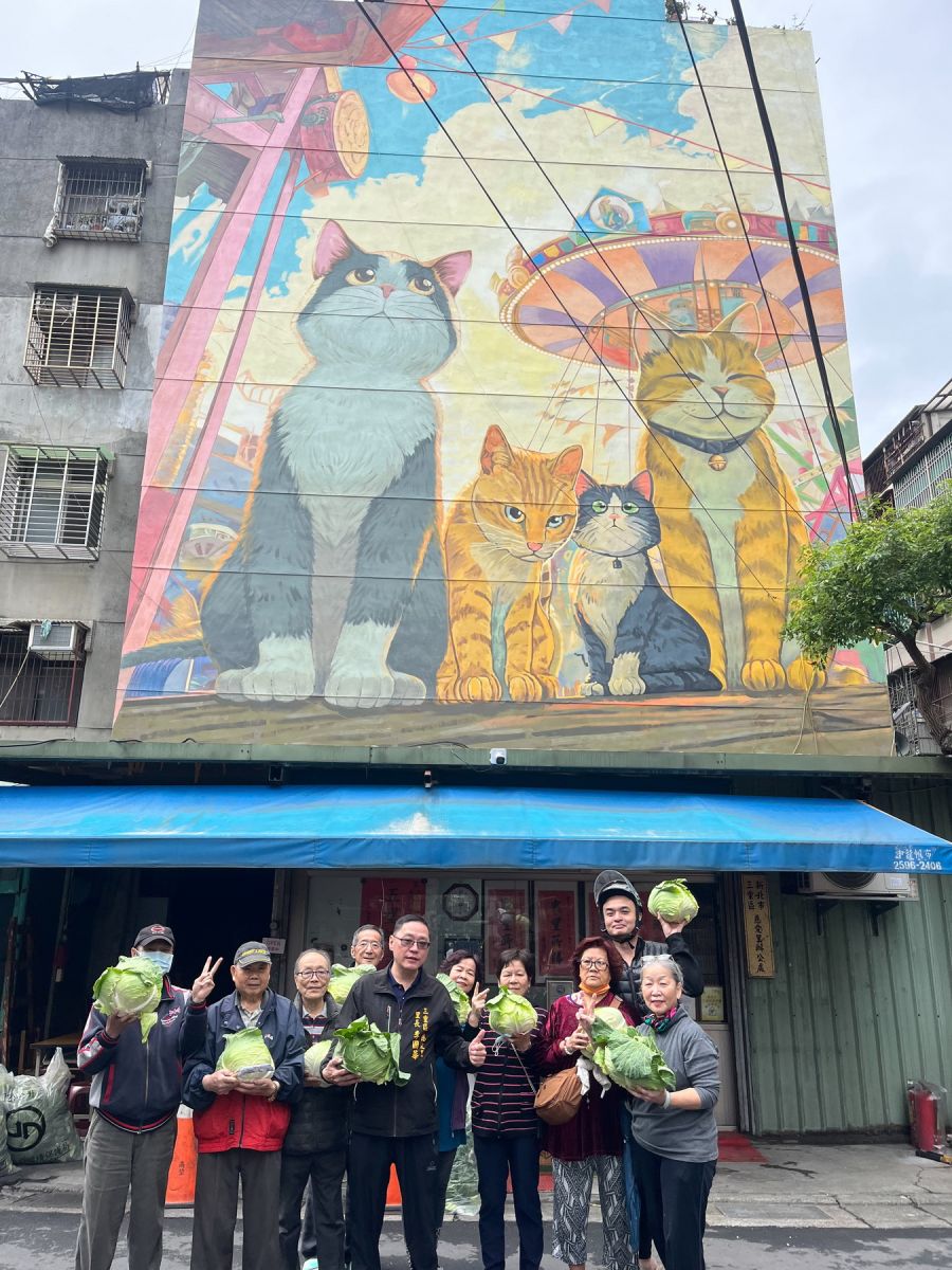 圖／不少里民手提高麗菜、在彩繪牆前拍照留念，直呼「有拿、有看、又療癒」。（新北市議員陳啟能辦公室提供）