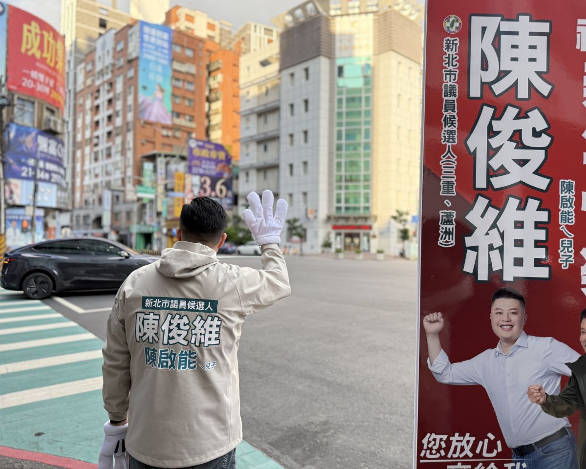 圖／陳俊維站上台北橋頭路旁，向往返雙北的通勤族揮手致意、祝福新年快樂。（新北市議員陳啟能辦公室提供）