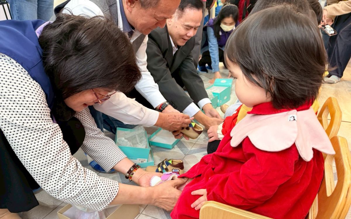 圖／社會局長李美珍等人幫幼兒穿上新鞋。（新北市政府社會局提供）